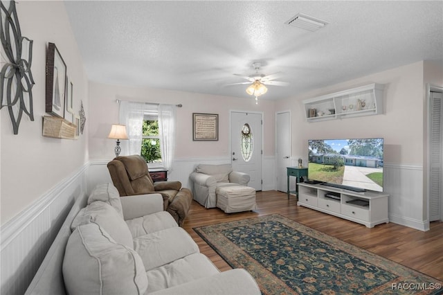 living room with ceiling fan, hardwood / wood-style flooring, and a textured ceiling