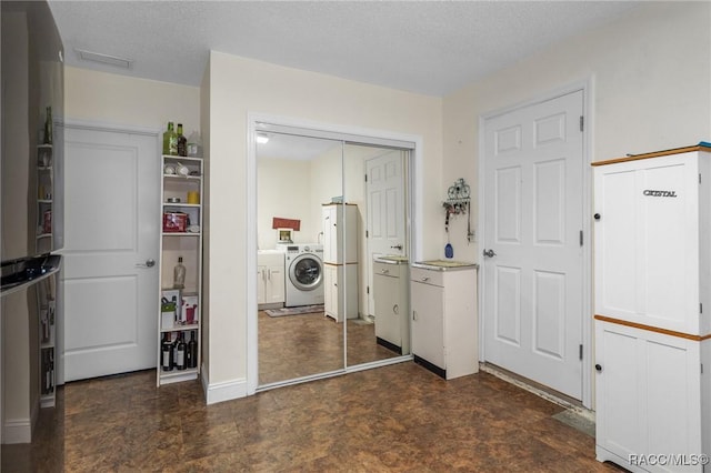 laundry area with washer and clothes dryer and a textured ceiling