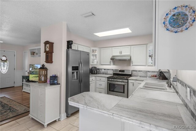 kitchen featuring sink, white cabinets, kitchen peninsula, stainless steel appliances, and a textured ceiling