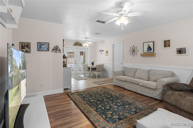 living room featuring ceiling fan, hardwood / wood-style floors, a textured ceiling, and french doors