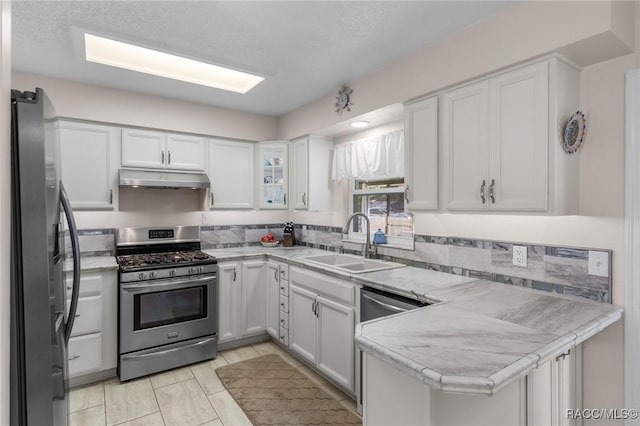 kitchen featuring sink, kitchen peninsula, white cabinets, and appliances with stainless steel finishes