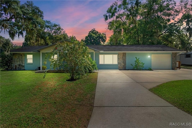 single story home featuring a garage and a yard