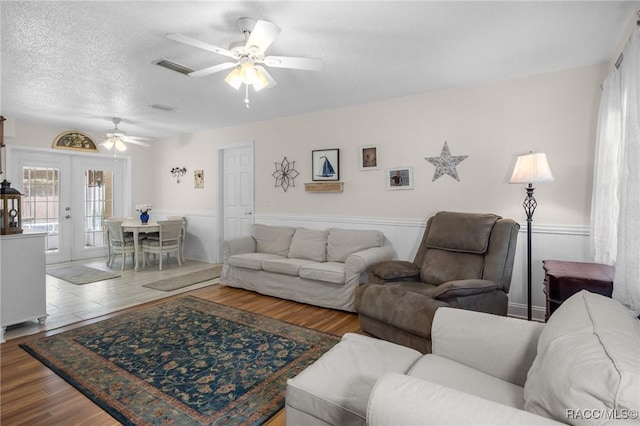 living room featuring french doors, ceiling fan, a textured ceiling, and hardwood / wood-style flooring