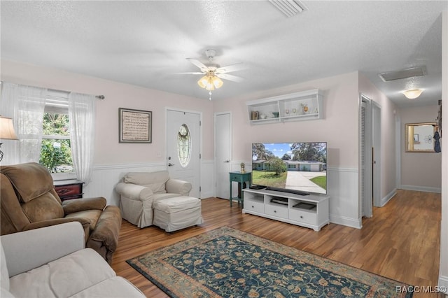 living room featuring ceiling fan, hardwood / wood-style floors, and a textured ceiling