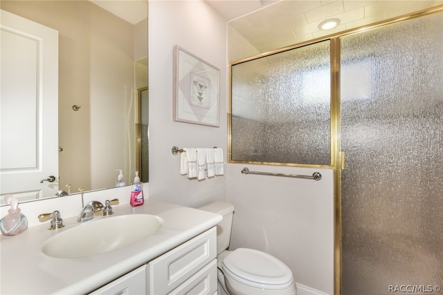 bathroom with vanity, toilet, and a shower with door