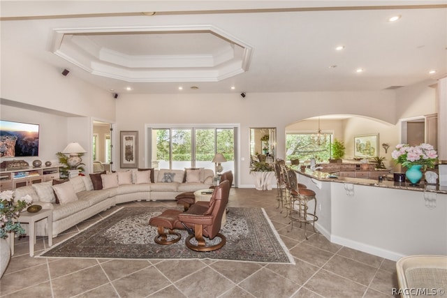 living room with a tray ceiling, tile patterned floors, and crown molding