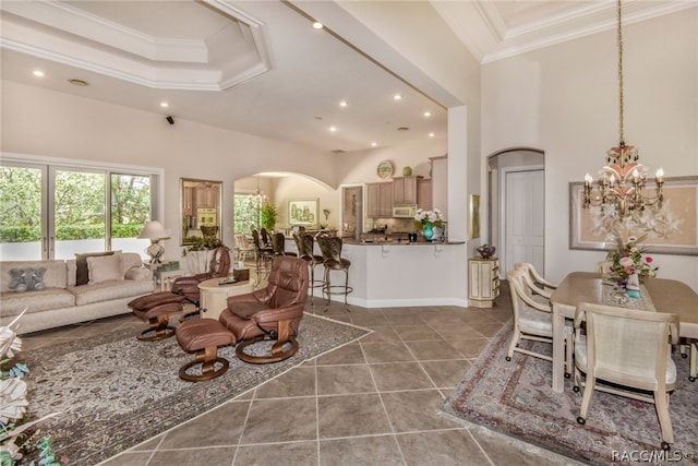 living room featuring tile patterned floors, crown molding, a high ceiling, and an inviting chandelier