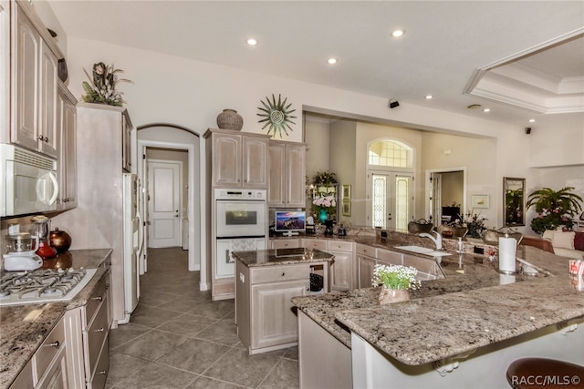 kitchen featuring light stone countertops, sink, a kitchen island, and white appliances