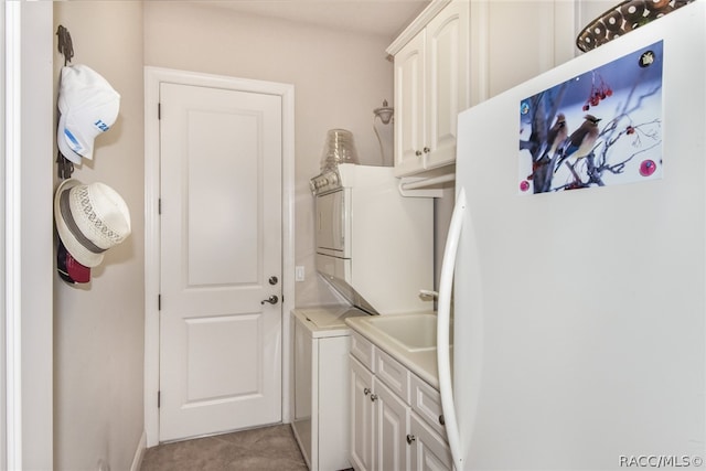 laundry room with cabinets, light tile patterned floors, and stacked washer / dryer