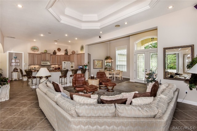 tiled living room featuring french doors, a tray ceiling, and crown molding