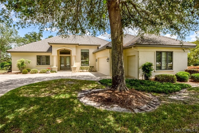 view of front of home with a front yard, french doors, and a garage