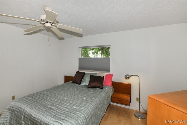 bedroom featuring ceiling fan, light hardwood / wood-style floors, and a textured ceiling