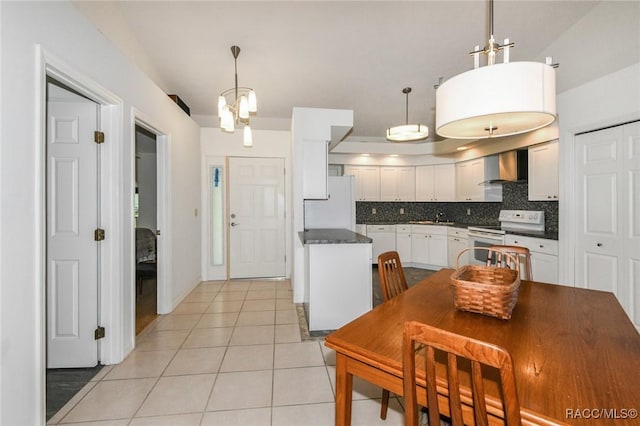 kitchen with backsplash, wall chimney range hood, white appliances, hanging light fixtures, and white cabinets