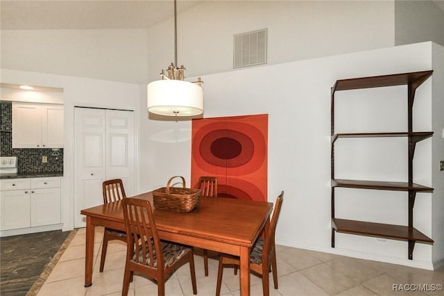 dining area with light tile patterned floors and high vaulted ceiling