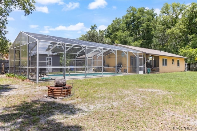 rear view of house with a lawn and glass enclosure