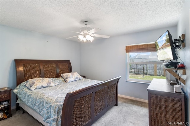 bedroom with ceiling fan, light colored carpet, and a textured ceiling