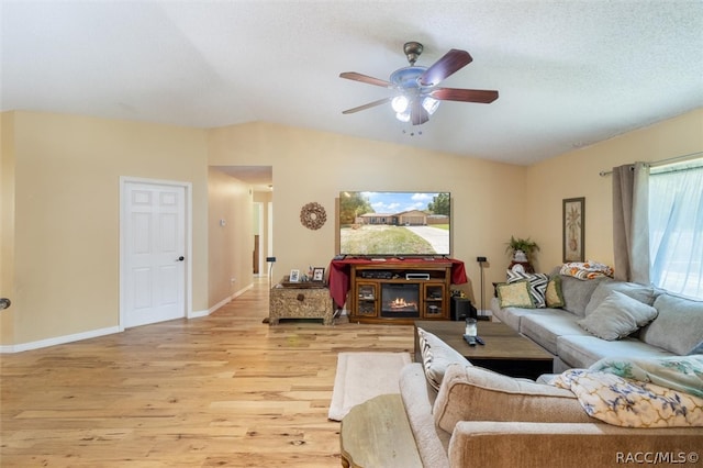 living room featuring a textured ceiling, ceiling fan, light hardwood / wood-style floors, and vaulted ceiling