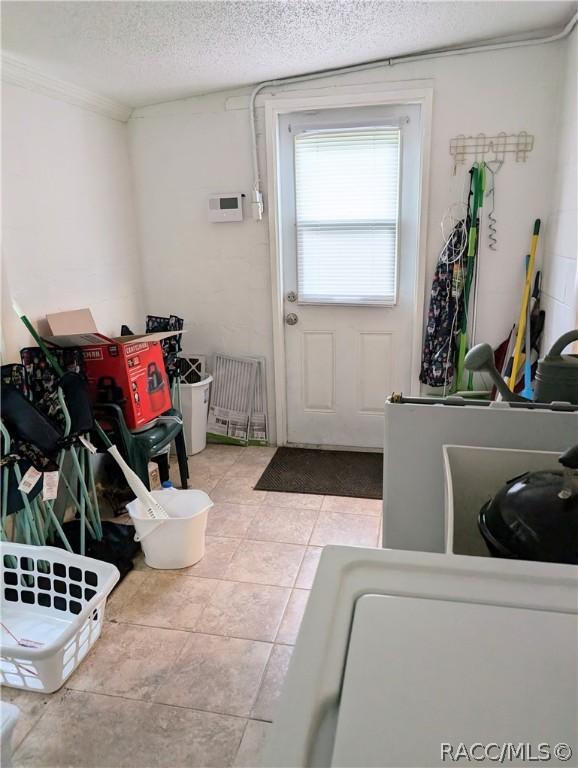 laundry area with light tile patterned floors and a textured ceiling