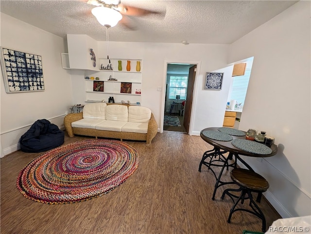 living room with a textured ceiling, ceiling fan, and dark hardwood / wood-style floors