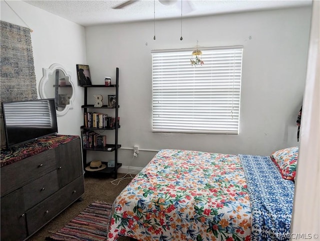 bedroom featuring baseboards, dark colored carpet, and a textured ceiling