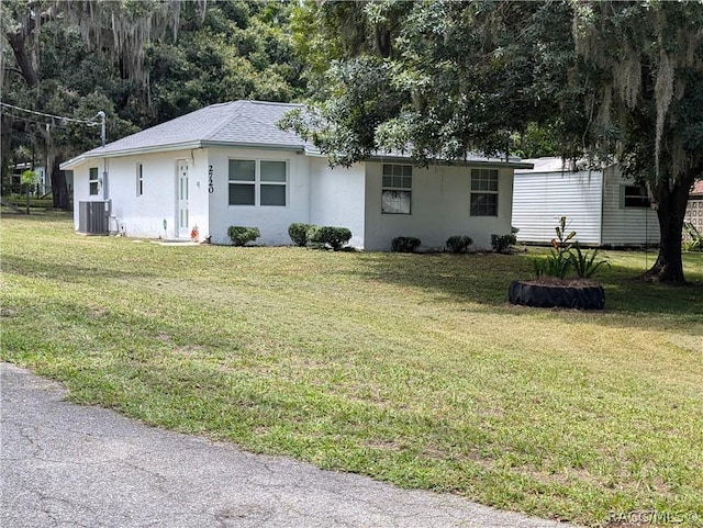 ranch-style home with stucco siding, roof with shingles, a front lawn, and central air condition unit