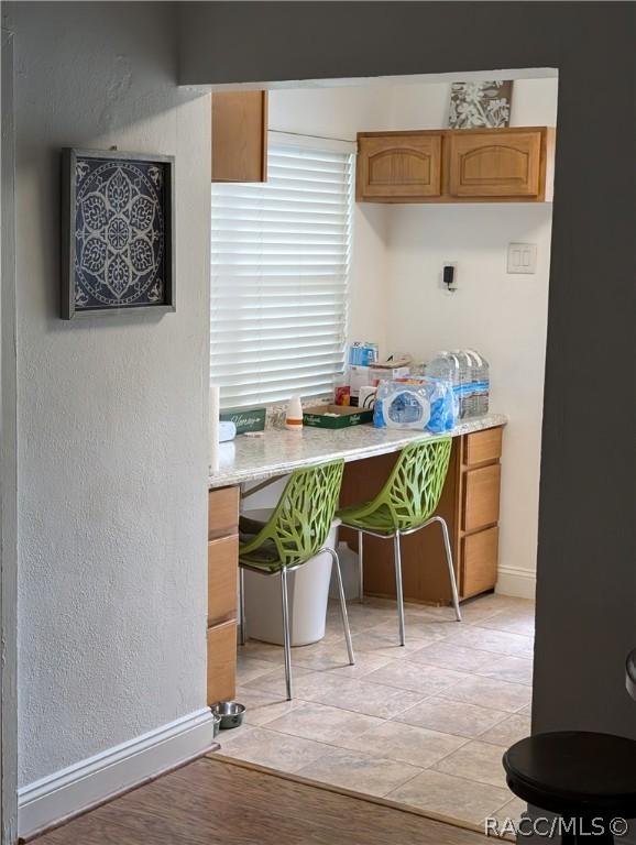 kitchen with a textured wall, light countertops, light wood finished floors, and baseboards