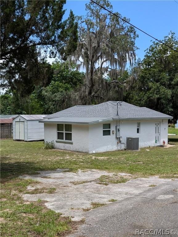 exterior space with an outbuilding, cooling unit, a lawn, and a storage unit