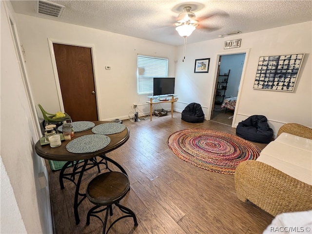 living room with hardwood / wood-style floors, ceiling fan, and a textured ceiling