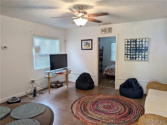 living room with ceiling fan, wood-type flooring, and a textured ceiling