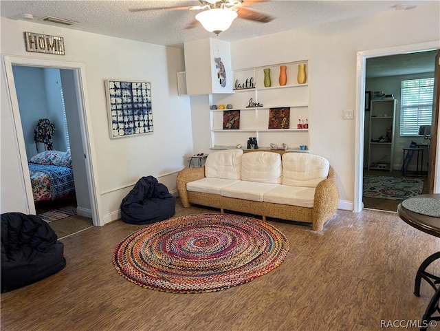 living room featuring hardwood / wood-style floors, a textured ceiling, and ceiling fan