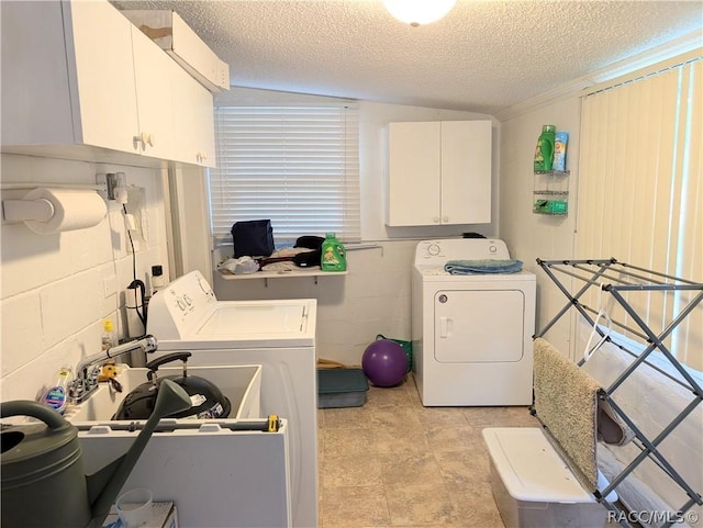 laundry area with concrete block wall, cabinet space, a textured ceiling, separate washer and dryer, and a sink