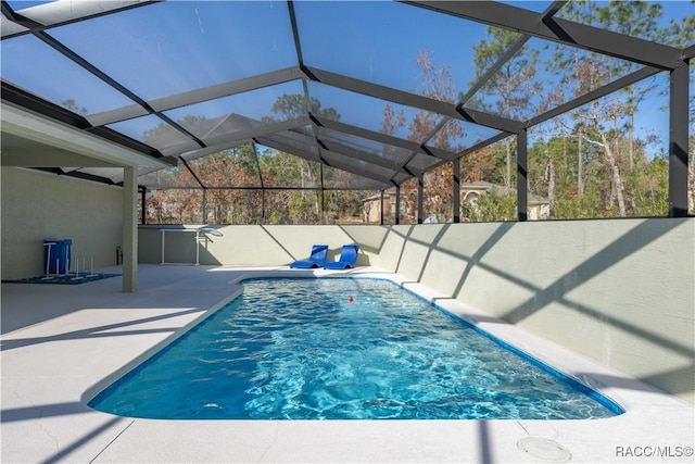 view of pool featuring glass enclosure and a patio area