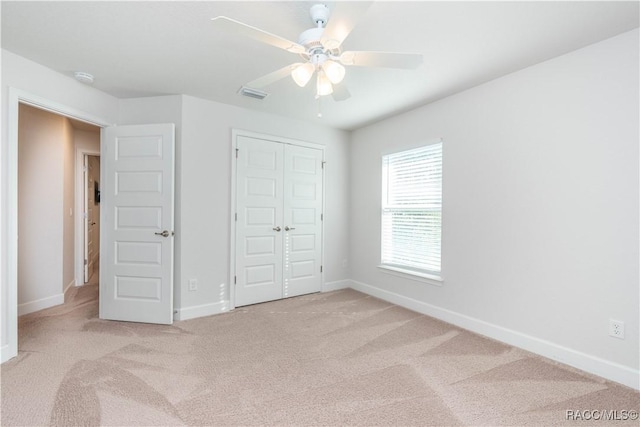 unfurnished bedroom featuring ceiling fan, light colored carpet, and a closet