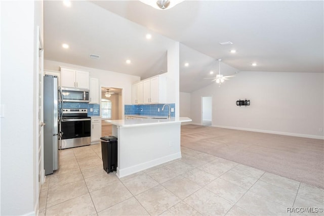 kitchen featuring kitchen peninsula, white cabinetry, stainless steel appliances, and lofted ceiling