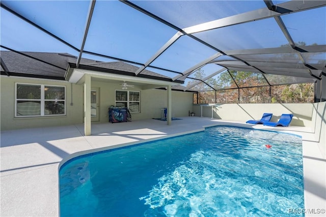 view of swimming pool with glass enclosure, ceiling fan, and a patio