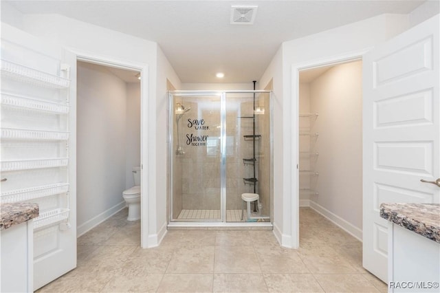 bathroom featuring tile patterned flooring, vanity, toilet, and a shower with door