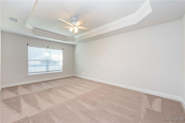 spare room featuring ceiling fan, ornamental molding, light carpet, and a tray ceiling