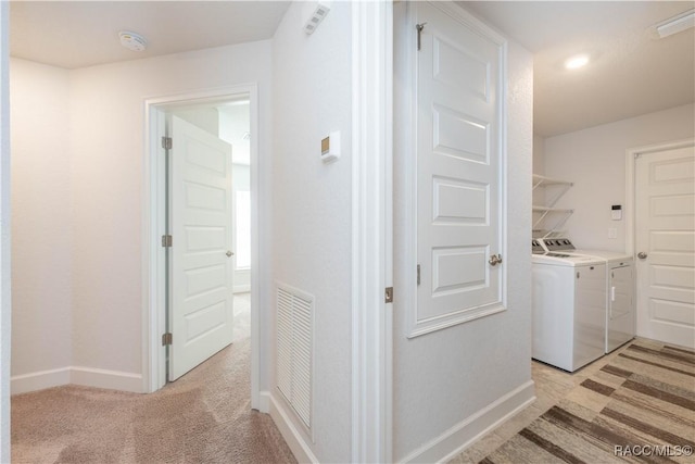 clothes washing area with washer and clothes dryer and light colored carpet