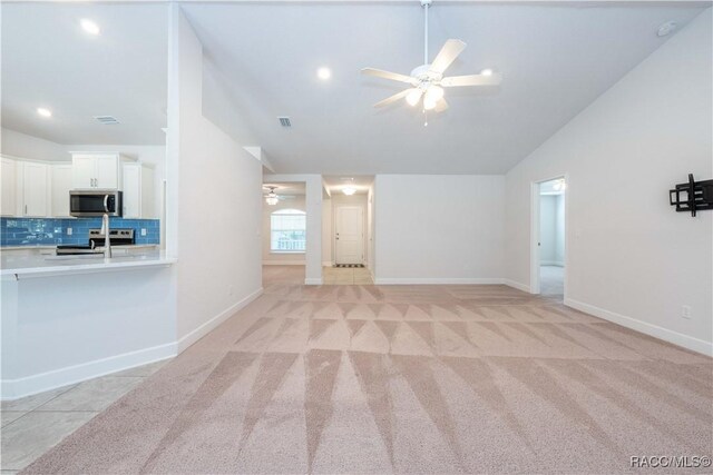 unfurnished living room with light carpet, ceiling fan, and lofted ceiling