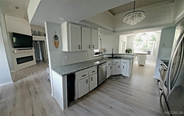 kitchen featuring sink, decorative light fixtures, dishwasher, white cabinets, and a chandelier