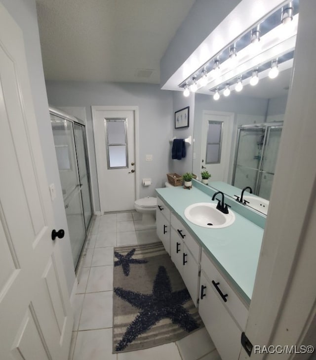 bathroom featuring tile patterned flooring, vanity, toilet, and walk in shower