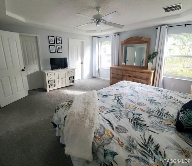 bedroom with carpet flooring, ceiling fan, a textured ceiling, and a tray ceiling