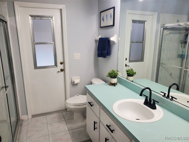 bathroom featuring tile patterned flooring, vanity, toilet, and walk in shower