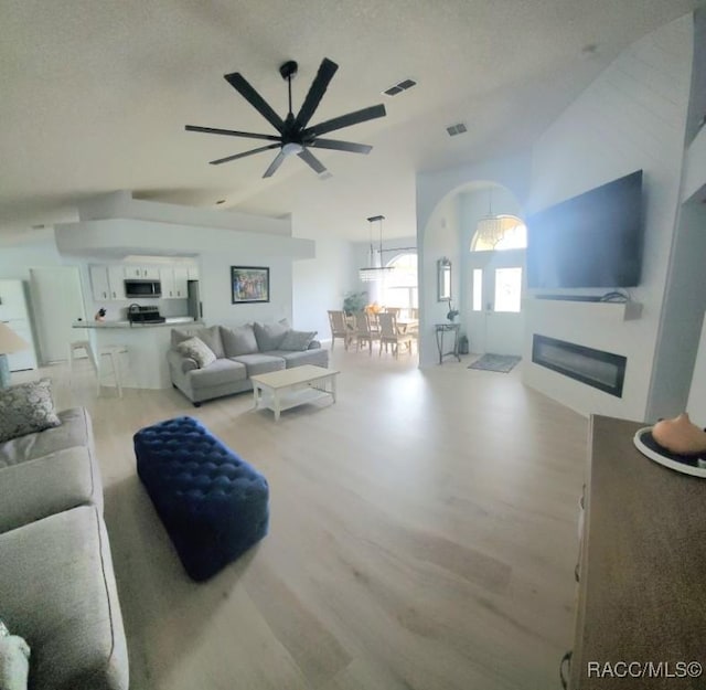 living room with light wood-type flooring, high vaulted ceiling, and ceiling fan