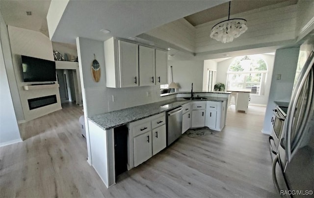 kitchen with pendant lighting, dishwasher, an inviting chandelier, sink, and white cabinetry