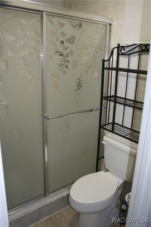 bathroom with hardwood / wood-style floors, toilet, and an enclosed shower