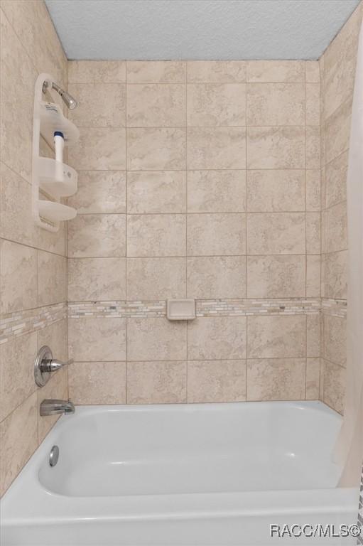 bathroom featuring shower / tub combo and a textured ceiling