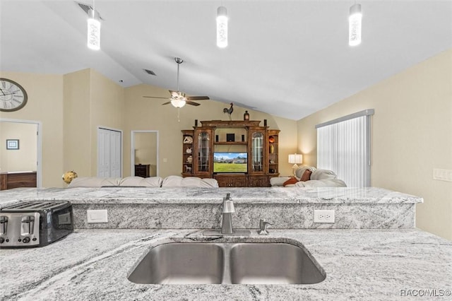 kitchen with sink, vaulted ceiling, light stone counters, and pendant lighting