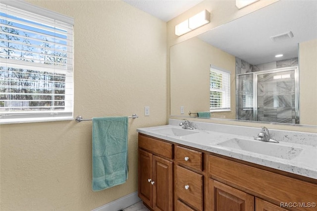 bathroom featuring a shower with shower door and vanity