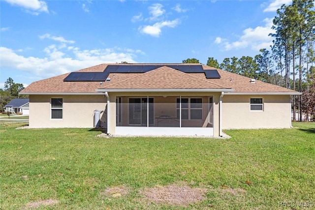 back of house featuring a sunroom, a lawn, and solar panels